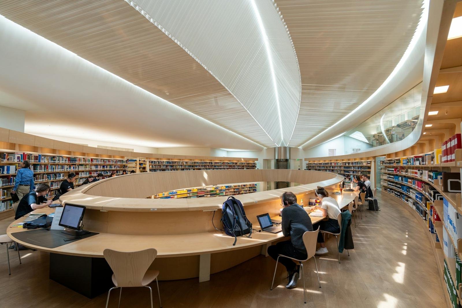 People reading at long tables in a public library