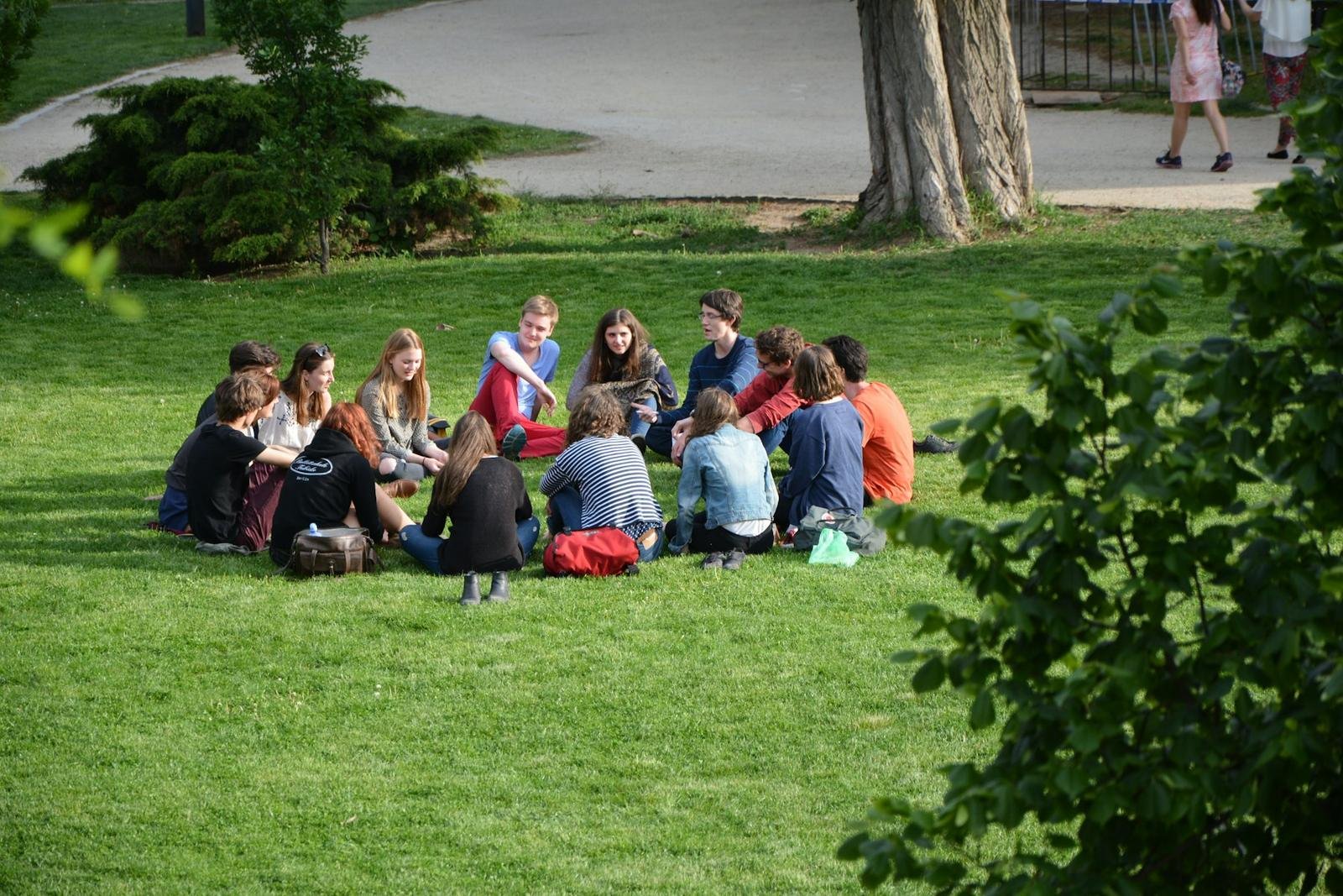 Young people sitting in a circle on the grass in a park