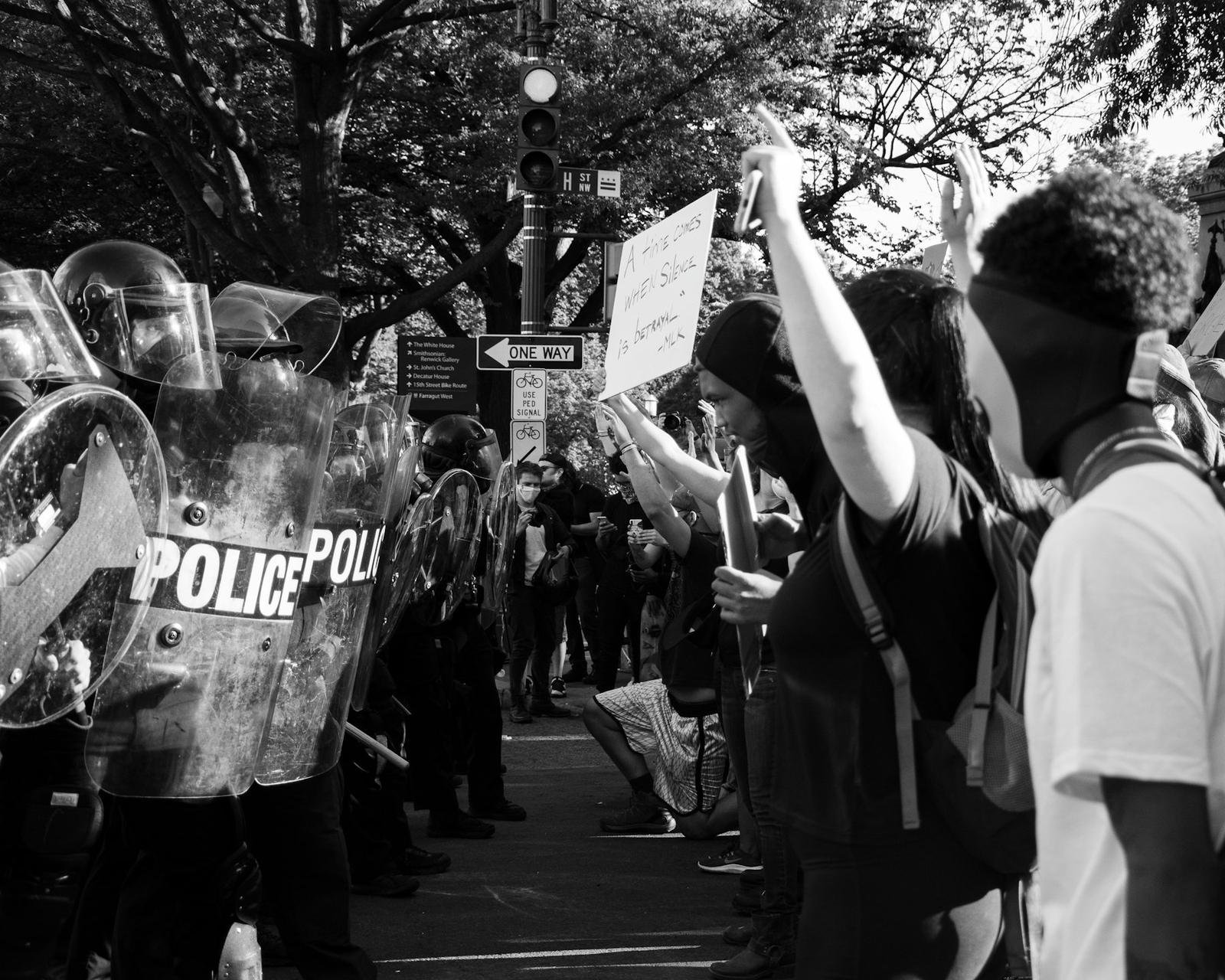 A protester holding a sign in front of a police line