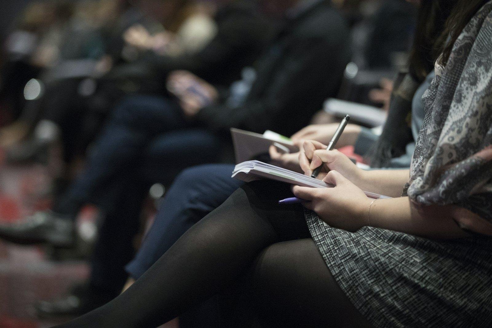 People in a meeting taking notes in their notebooks
